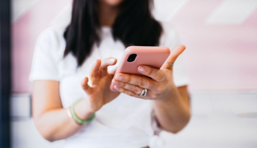 A woman is holding a pink cell phone.