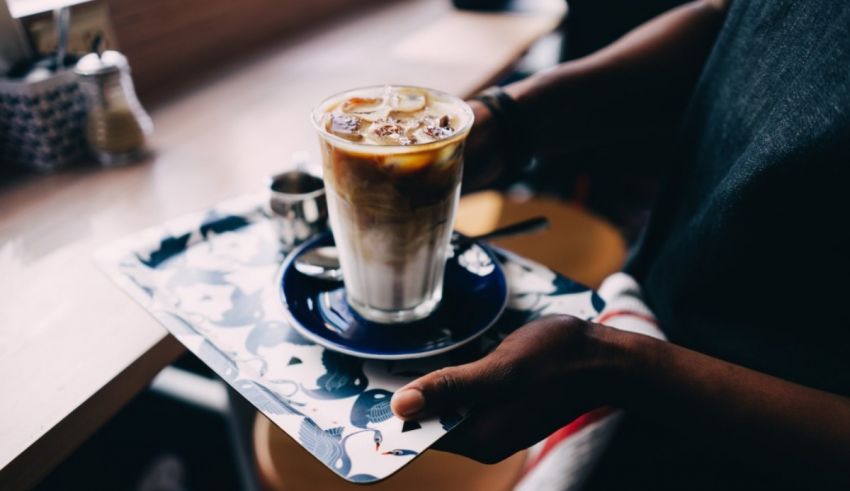 A man is holding an iced coffee on a tray.