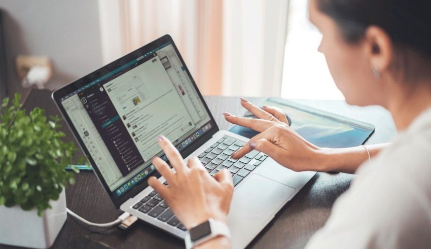 A woman is using a laptop on a desk.