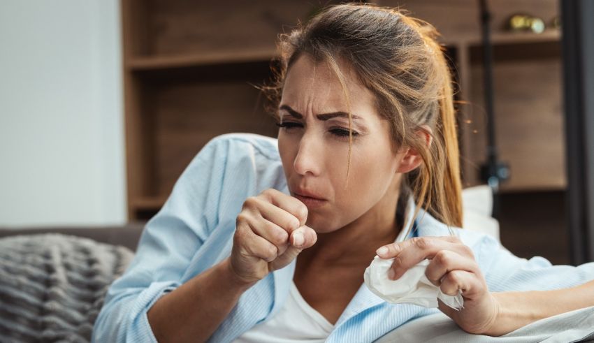A woman is laying on a couch with a tissue in her hand.