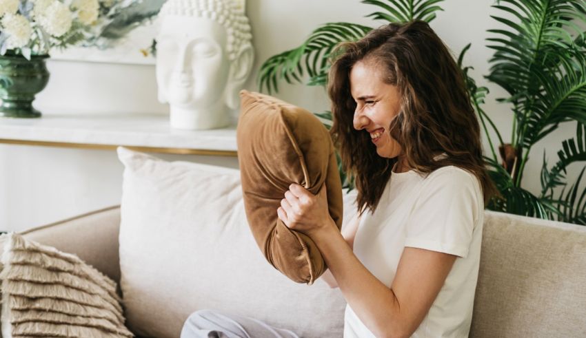 A woman is sitting on a couch and holding a pillow.