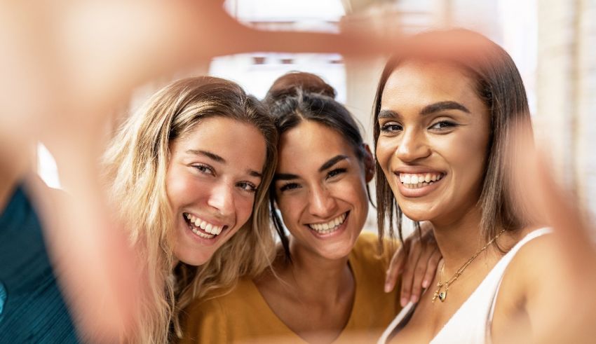 Three young women are taking a selfie with a frame.