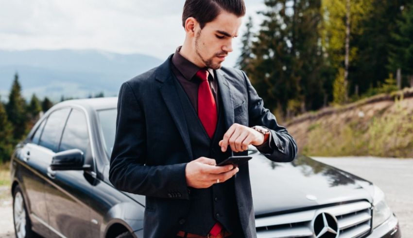A man in a suit standing next to a mercedes benz.