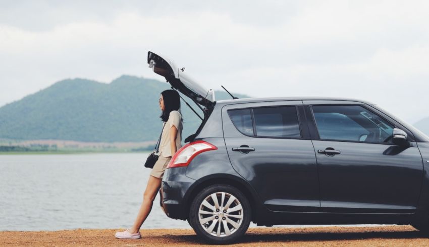 A woman is standing next to a car with its trunk open.