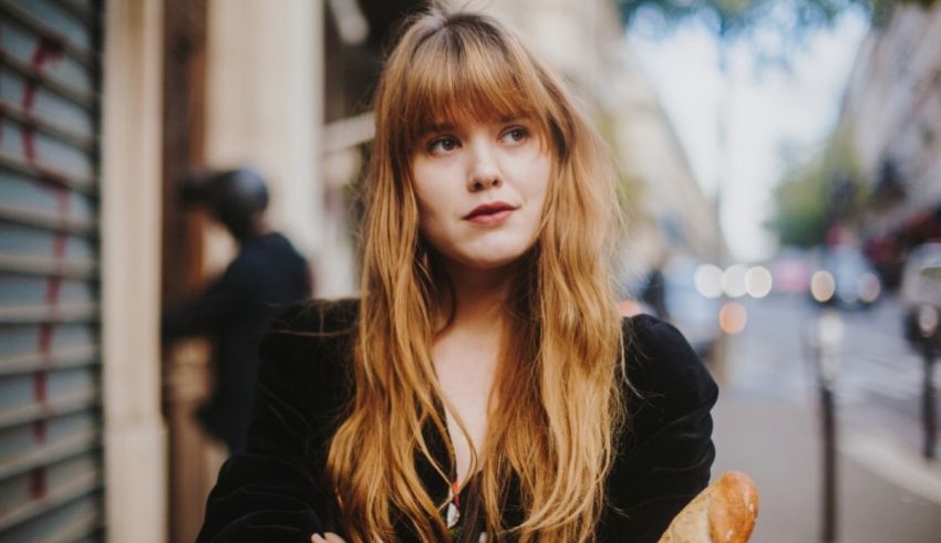 A young woman is standing on a street with her arms crossed.