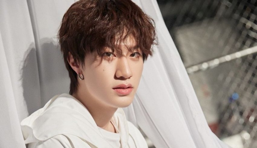 A young man in a white shirt is posing for a photo.