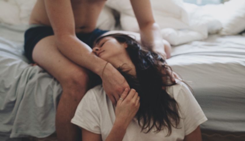 A man and woman hugging on a bed.