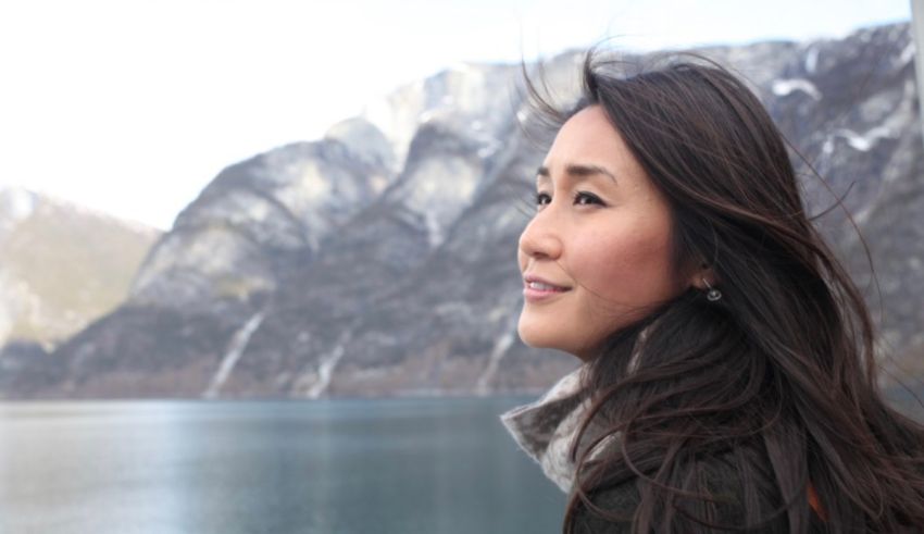 A woman looking out over a lake with mountains in the background.