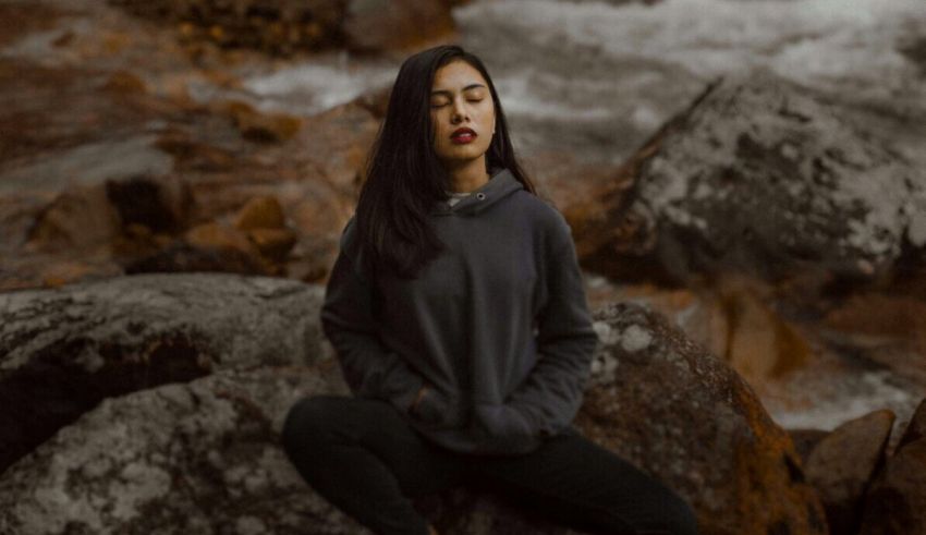A woman sitting on rocks near a river.