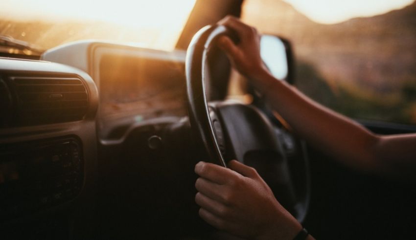 A woman driving a car at sunset.