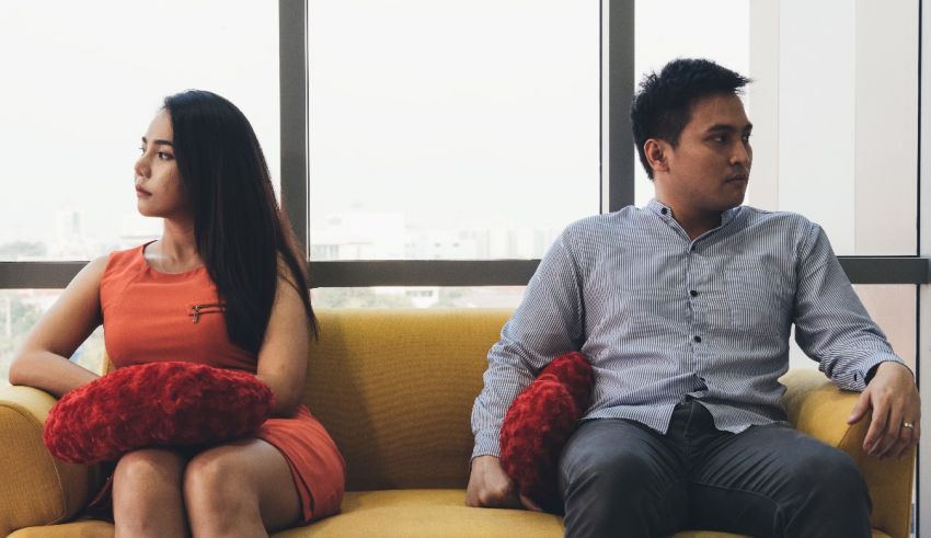 A man and woman sitting on a yellow couch.