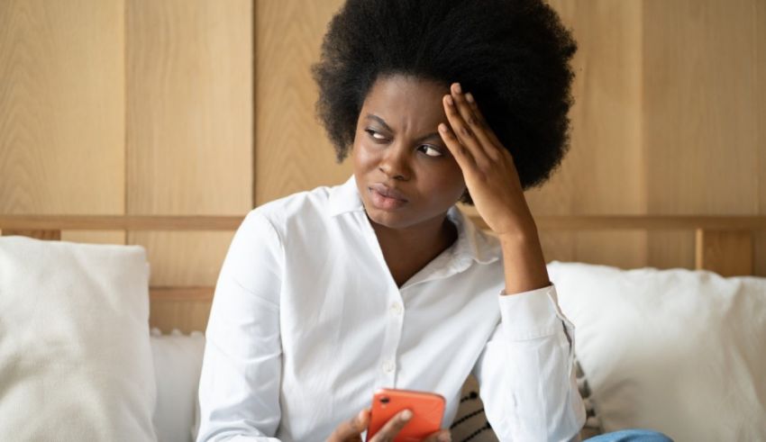 A woman sitting on a bed looking at her phone.