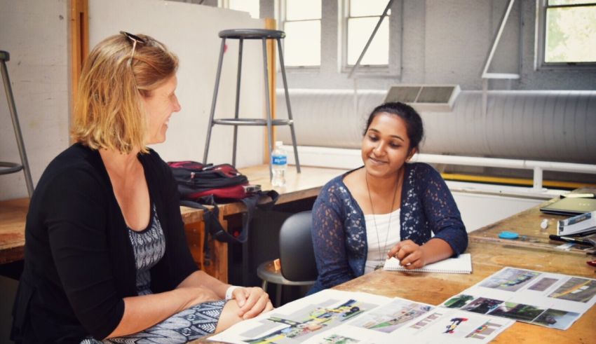 Two women sitting at a table talking to each other.