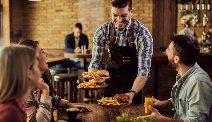 A waiter serving food to a group of people at a restaurant.