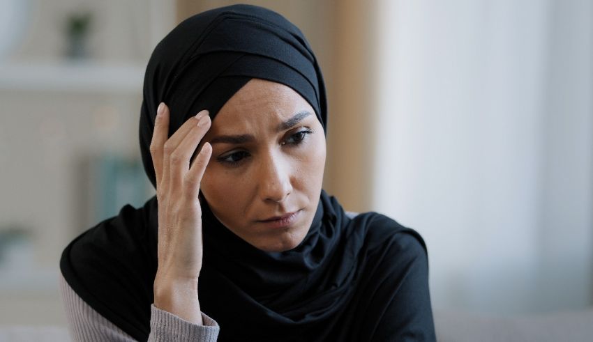 A muslim woman in a black hijab sitting on a couch.