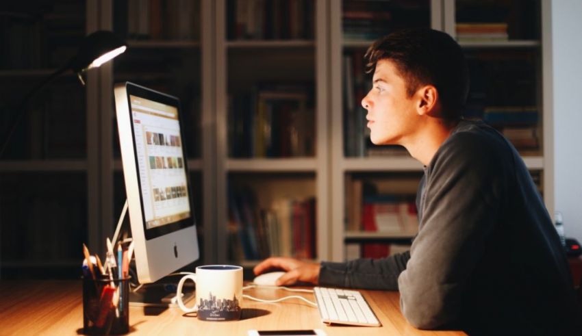 A man sitting at a desk looking at a computer screen.