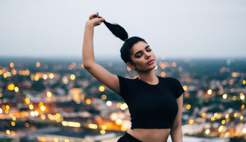A young woman posing in front of a city at night.