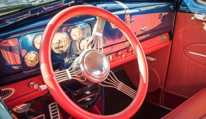 The interior of a classic car with a steering wheel and gauges.