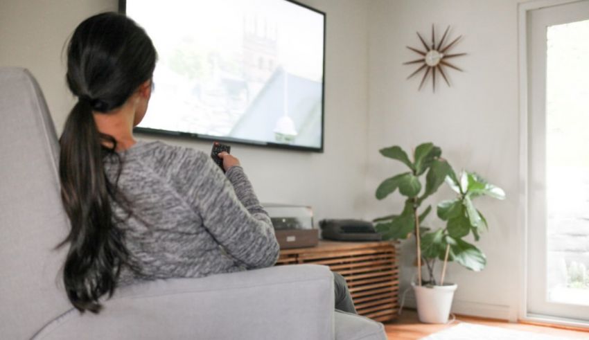 A woman sitting in a chair watching tv.
