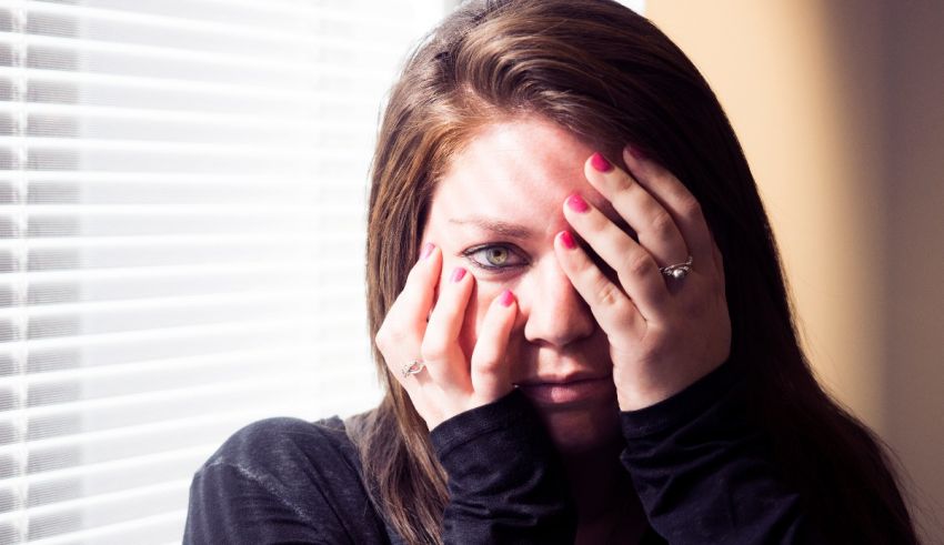 A woman covering her face with her hands.