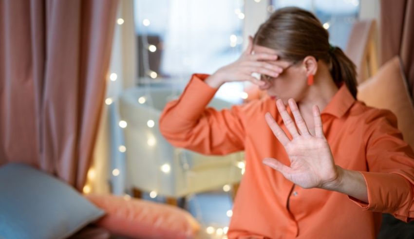 A woman is making a stop sign in front of a christmas tree.