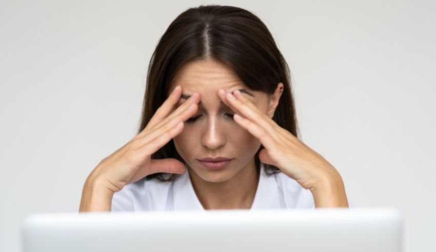 A woman with her hands on her head looking at her laptop.