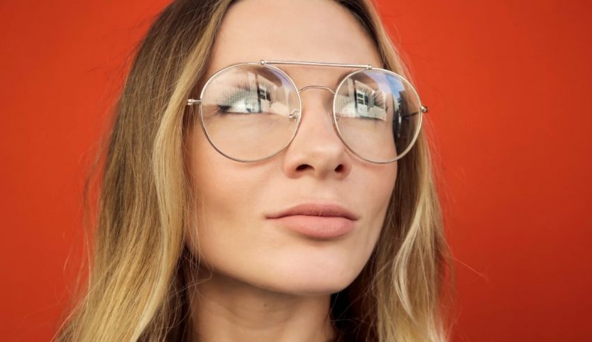 A woman wearing glasses on a red background.