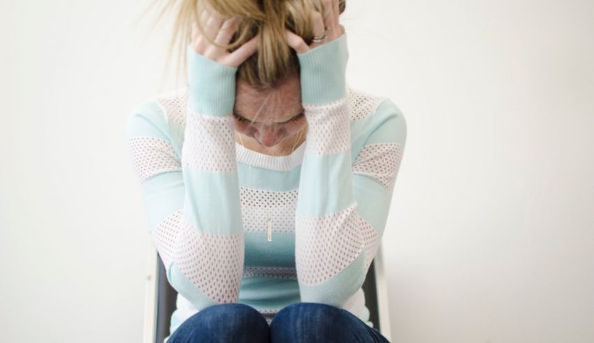 A woman sitting on a chair with her hands on her head.