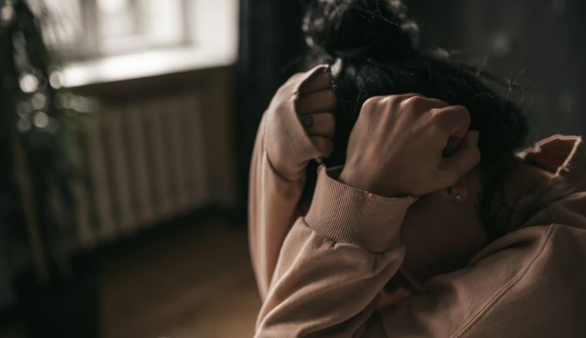 A woman covering her face with her hands.