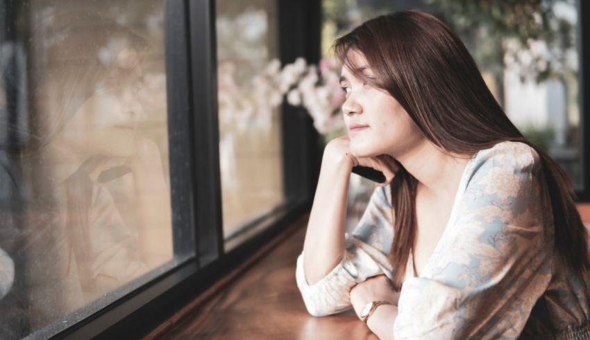 A woman sitting at a table looking out a window.
