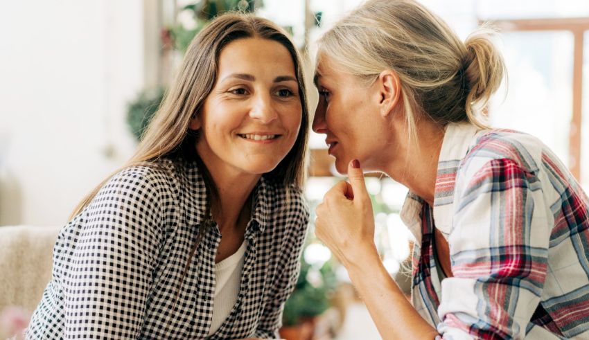 Two women sitting on a couch talking to each other.