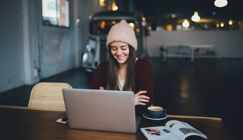 A woman sitting at a table with a laptop and a cup of coffee.