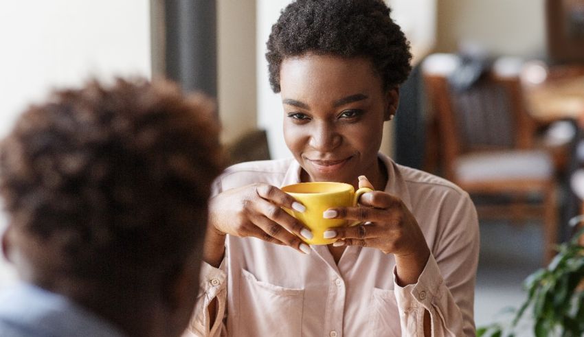 A woman is sitting at a table with a cup of coffee.