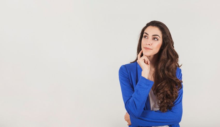 A young woman with long hair and a blue cardigan posing in front of a white background.