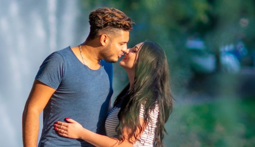 A man and woman kissing in front of a fountain.