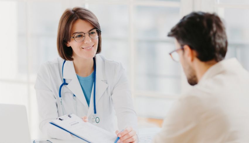 A male doctor talking to a female patient in a doctor's office.