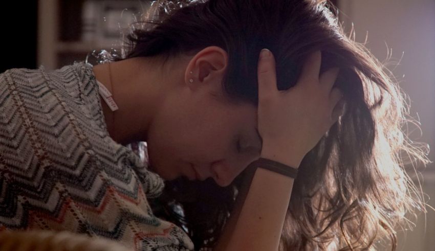 A woman with her head on her head in front of a window.