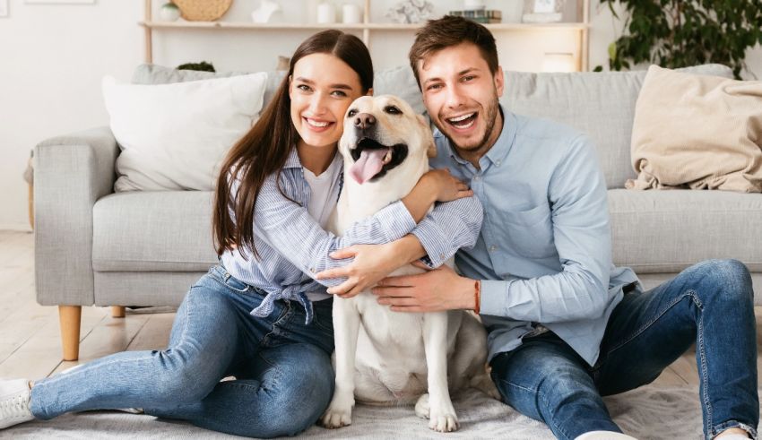 Young couple sitting on the floor with their dog at home.