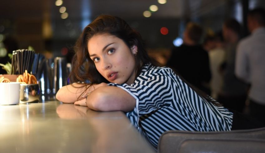 A young woman leaning over a bar.