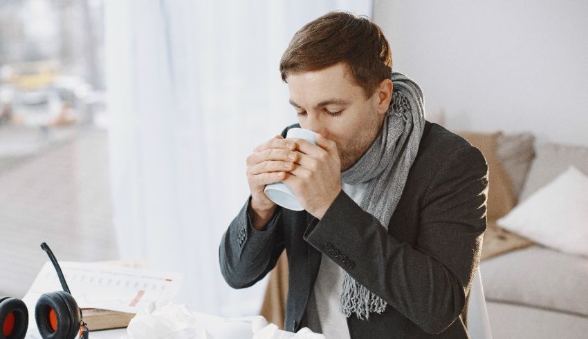 A man drinking a cup of coffee while sitting at his desk.