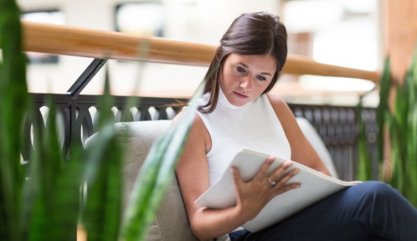 A woman sitting on a bench reading a book.