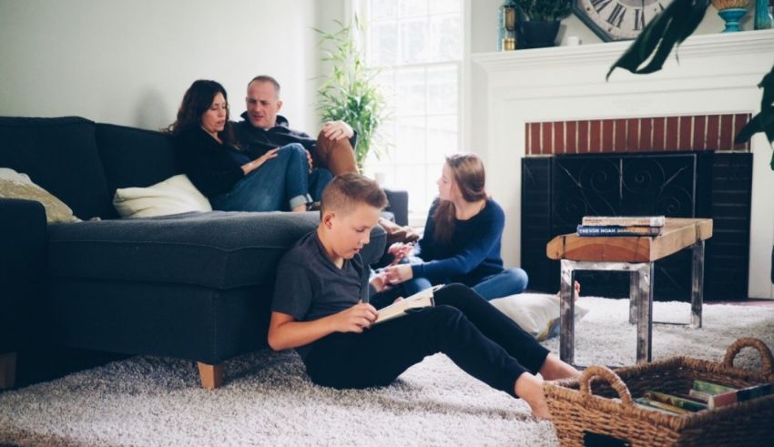A family sits on the floor in front of a fireplace.