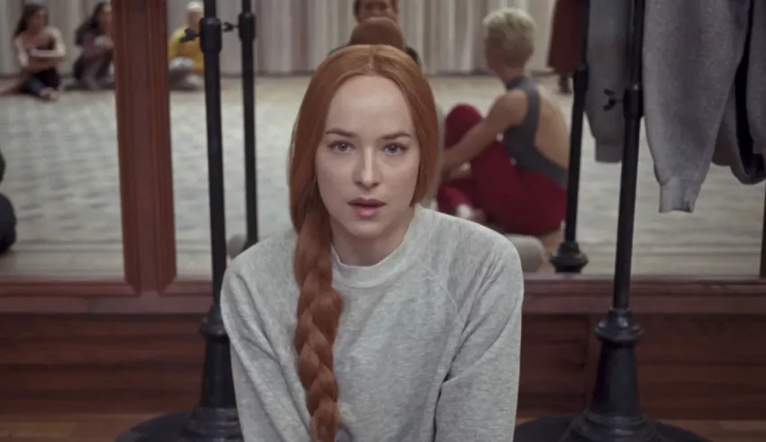 A woman with long red hair is sitting in front of a group of people.