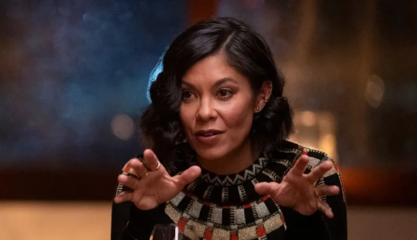 A woman is sitting at a table and gesturing.